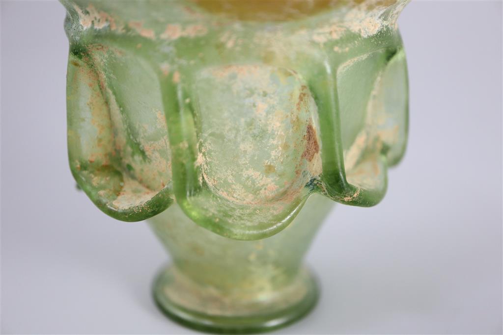 A Roman green glass auricular cup, 2nd/3rd century AD, 7.5cm high